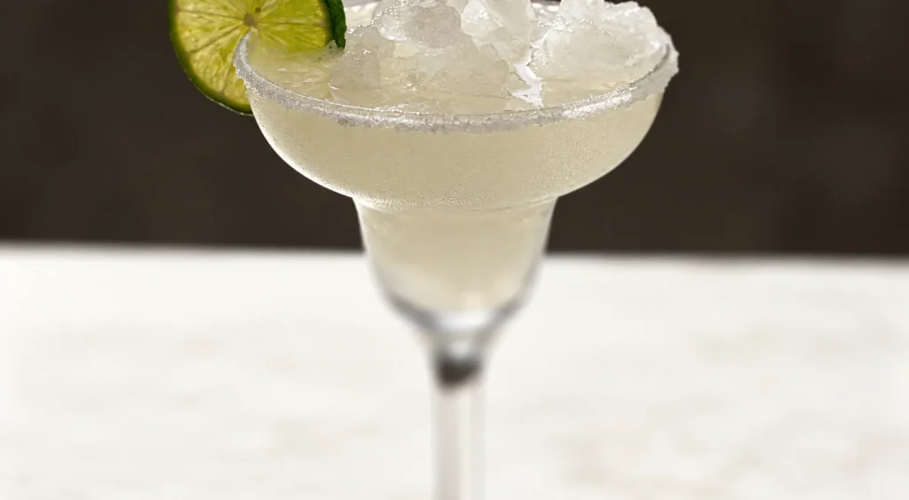 Cloudy margarita with crushed ice, a salted rim and lime wheel.