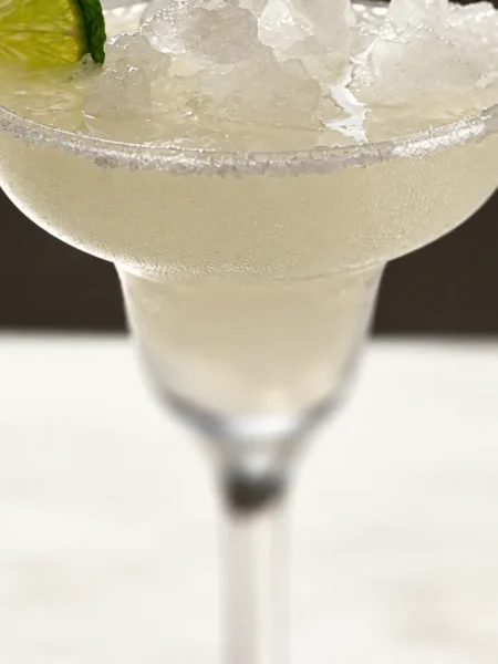 Cloudy margarita with crushed ice, a salted rim and lime wheel.