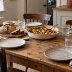 An inviting kitchen table set for four with bread, a shared dish and water glasses