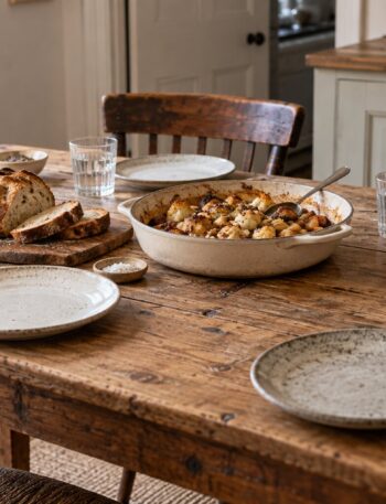 An inviting kitchen table set for four with bread, a shared dish and water glasses